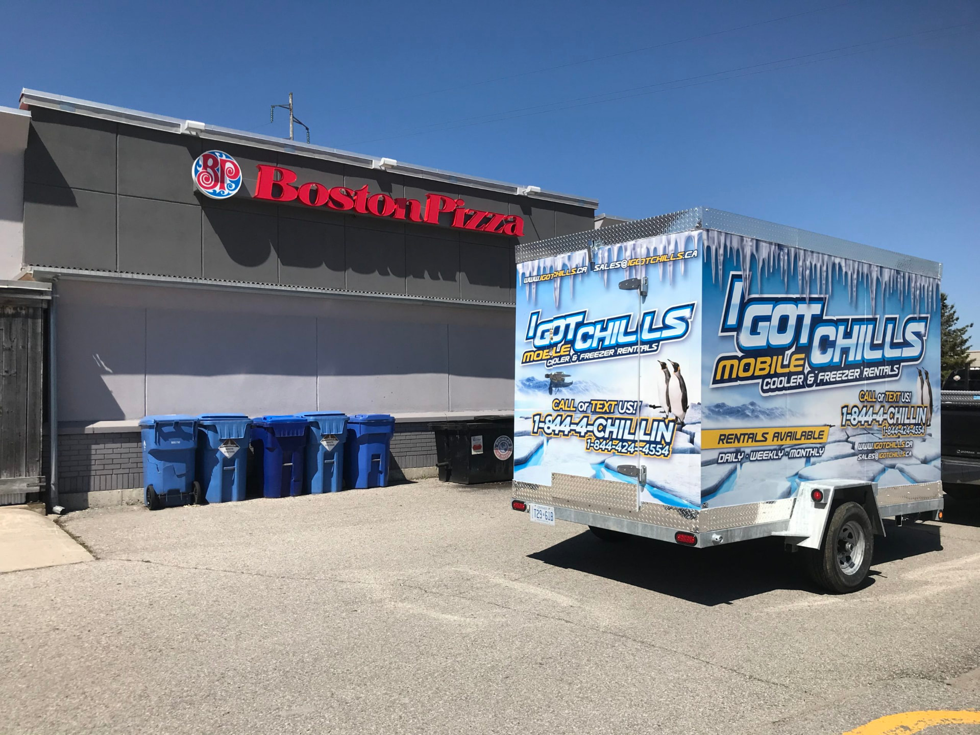 Refrigerated rental trailer parked behind a Boston Pizza restaurant